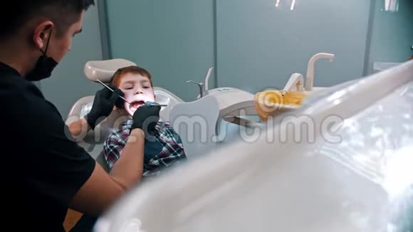 一个在牙科治疗的小男孩拿着镜子看着镜子视频的预览图