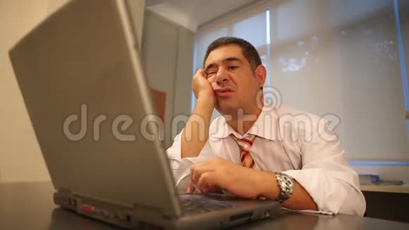 困的商人在办公室里用笔记本电脑视频的预览图