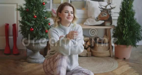 欧洲年轻迷人的女士穿着温暖的毛衣坐在斯堪的纳维亚内部舒适的圣诞家庭氛围和舒适的家庭氛围视频的预览图