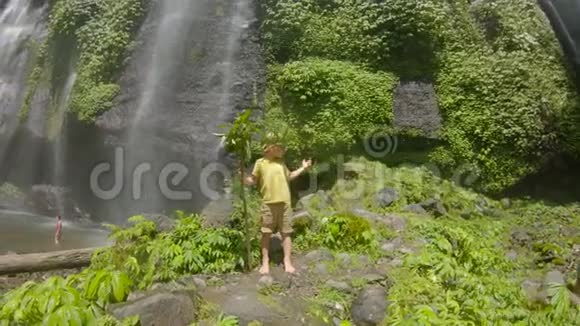 一位快乐的儿童游客参观巴厘岛美丽的斐济瀑布前往巴厘概念视频的预览图