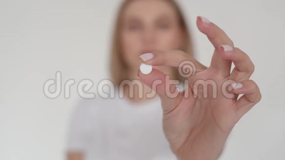 相机里一块白色的平板电脑女孩把药丸放在手臂的长度上然后喝了它女孩视频的预览图