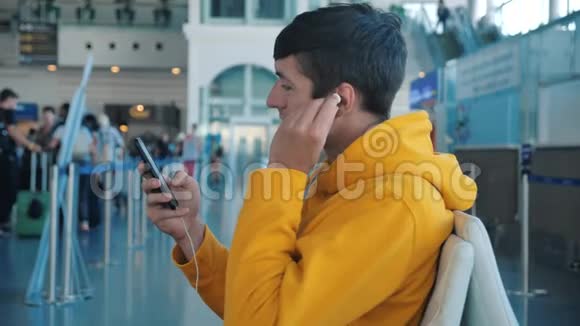 年轻人坐在靠近窗户的机场用电话模糊的飞机背景坐飞机的家伙视频的预览图