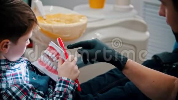 一个在牙科治疗的小男孩那个在塑料人下巴模型上刷牙的孩子视频的预览图