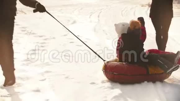 一个男人父亲把他的孩子卷在充气雪橇上视频的预览图