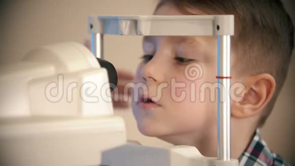 一个小男孩在眼科诊所接受治疗一个小男孩在检查设备的镜头视频的预览图