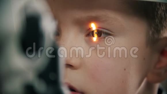 一个在眼科诊所接受治疗的小男孩眼睛里闪着亮光视频的预览图