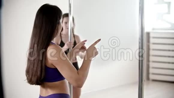 两个身材窈窕的黑发女人在白人工作室接受钢管舞训练视频的预览图