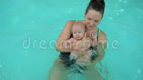年轻的妈妈和她的小女儿在游泳池里做水处理新生儿保健用水程序视频的预览图
