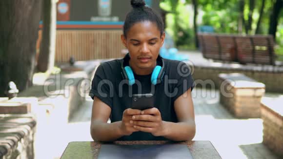 肖像帅哥坐在公园发短信用手机视频的预览图