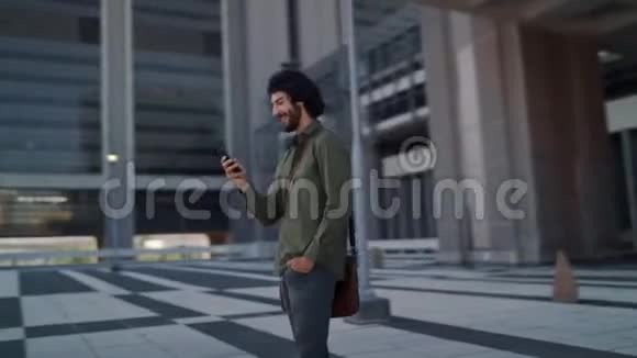 360种程度的旋转视角一个快乐的职业男性使用他的智能手机站在城市公寓或视频的预览图