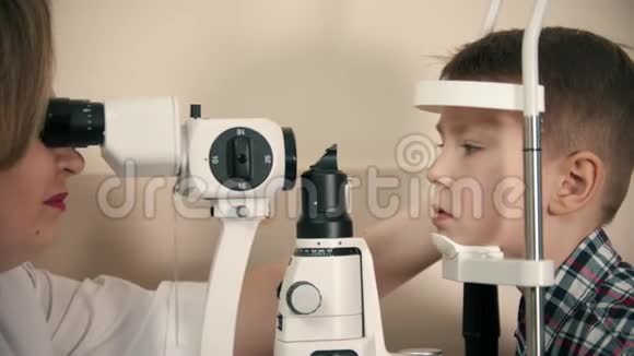 一个在眼科诊所接受治疗的小男孩一位女医生通过一个大的特殊检查来检查视力视频的预览图