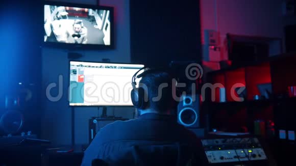 一位戴耳机的男声工程师在霓虹灯录音室工作录制说唱曲目视频的预览图