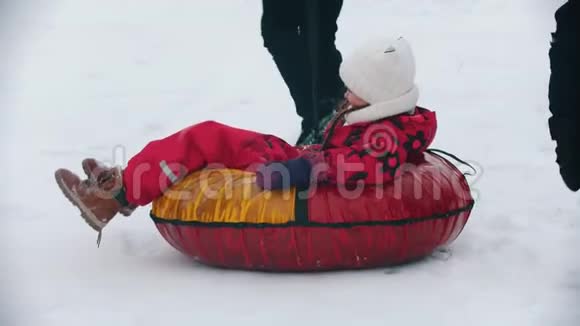 一家人在森林附近的户外跑步和玩耍男人把他的女儿卷在充气雪橇上视频的预览图