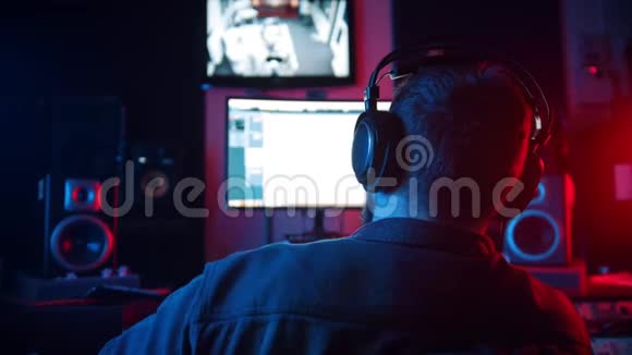 一位男声工程师戴着耳机坐在录音室里在跑道上工作视频的预览图