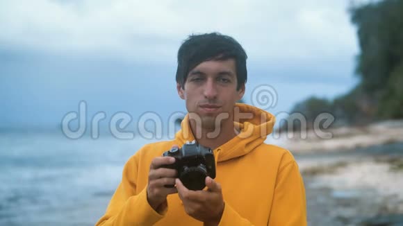 晚上穿黄色连帽衫的男摄影师在美丽的热带海滩上拍照视频的预览图