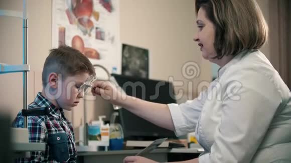 眼科诊所的一种治疗方法一个小男孩在纸上读信医生在男孩眼前换镜片视频的预览图