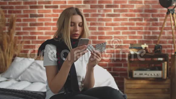 一个脖子上戴着围巾的生病的女孩读着一张药丸的处方坐在床上沉重地叹了口气这就是视频的预览图