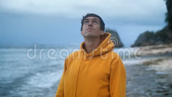一位年轻的男性旅行者在雷雨前在一个野生热带海滩上的肖像视频的预览图