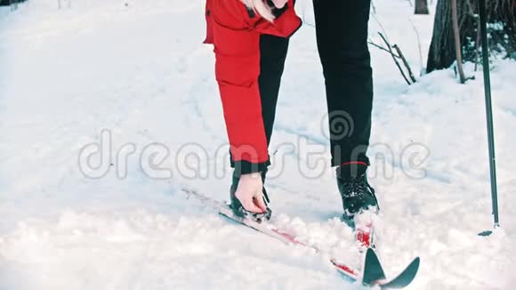一个穿着红色羽绒服的女人从滑雪场上脱下靴子视频的预览图