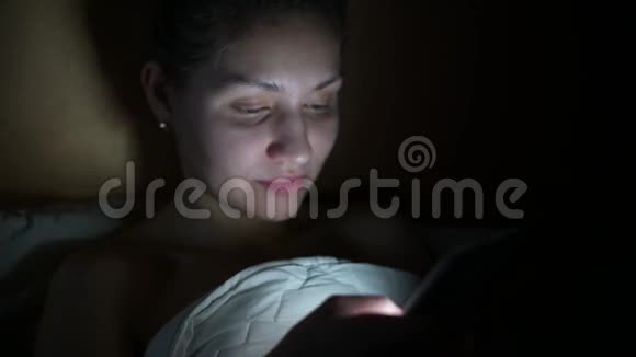 躺在床上的女孩在手机上浏览社交网络视频的预览图