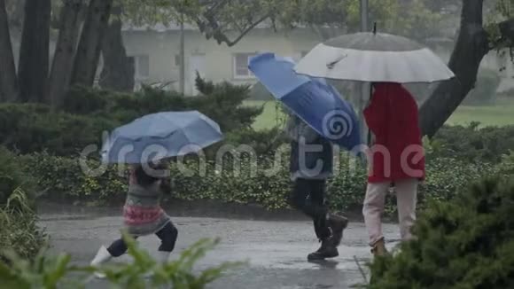 孩子们在倾盆大雨中享受着用雨伞跳跃的乐趣慢动作视频的预览图