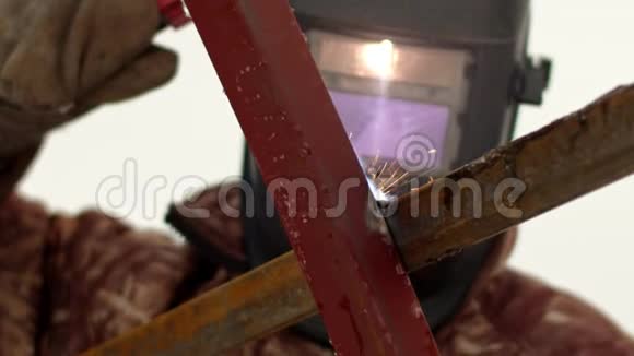 从蒙面焊工焊接金属框架的金属结构内部的视图焊接产生的火花和火花视频的预览图