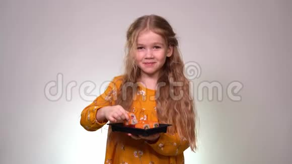 小女孩咬着美味的面包卷手里拿着视频的预览图