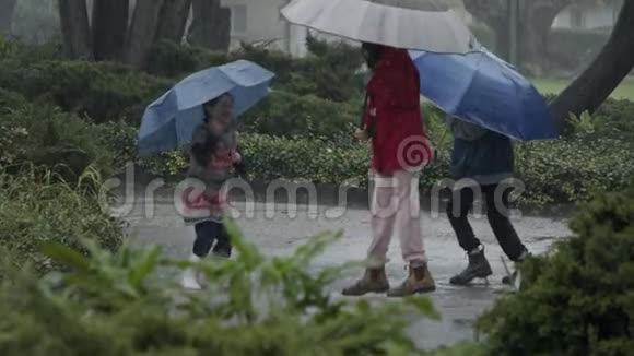 孩子们在倾盆大雨中享受着用雨伞跳跃的乐趣慢动作视频的预览图
