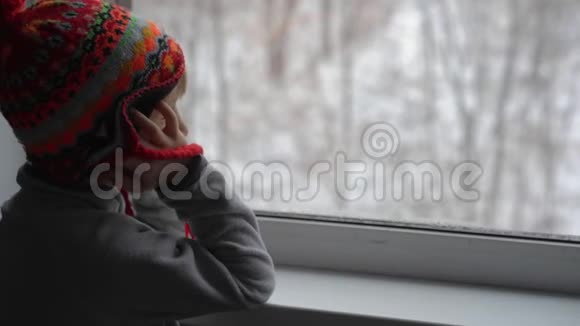 一个小男孩透过窗户望着一场大雪等待圣诞节的到来视频的预览图