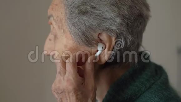 老妇人使用无线耳机老年人和技术视频的预览图
