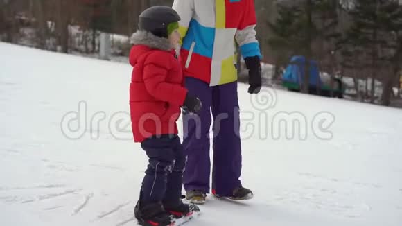 年轻人滑雪板教练教小男孩如何骑滑雪板冬季活动概念视频的预览图