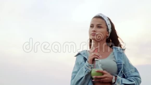 白种人外表的女孩手里拿着夏季城市鸡尾酒欣赏着美丽的景色视频的预览图