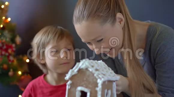 年轻的女人和她的小儿子做了一个姜饼屋家庭假日概念圣诞节概念视频的预览图