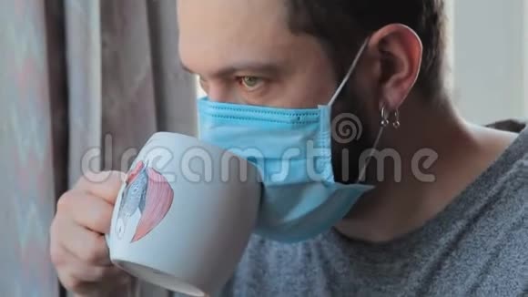 冠状病毒的乐趣有趣的人在家喝茶通过保护面具在家疯狂在检疫男性特写视频的预览图