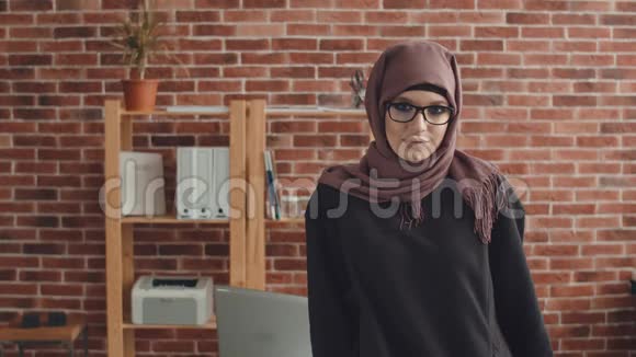 一个开朗的穆斯林女人站在办公室笑戴着黑头巾的快乐少女微笑着笑视频的预览图