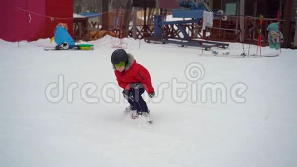 小男孩在滑雪板的第一课上摔倒了冬季活动概念慢镜头视频的预览图