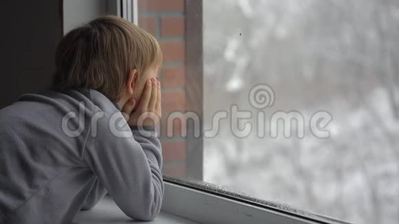 一个小男孩透过窗户望着一场大雪等待圣诞节的到来视频的预览图