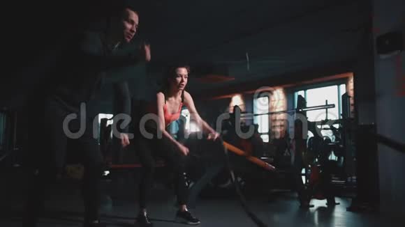 运动女性与私人教练在现代健身房锻炼绳索视频的预览图