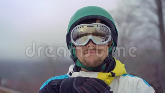 一个穿着雪谷歌的年轻人的特写镜头看着一台照相机寒假概念慢镜头视频的预览图