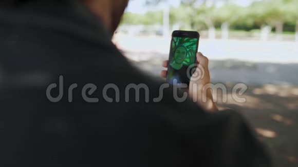 一个耳朵里有耳机的男人通过一个视频电话在智能手机上做拇指与他的朋友交谈的后视镜视频的预览图