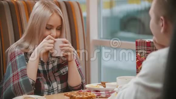 一个年轻的金发女人在咖啡馆里喝咖啡和男朋友聊天视频的预览图