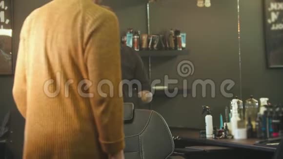 一个头发湿的年轻人坐在理发店的椅子上视频的预览图