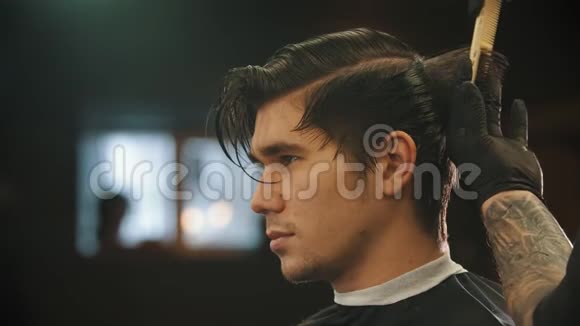 一个年轻男子在理发店理发时被纹身的理发师戴着黑手套剪了指甲视频的预览图