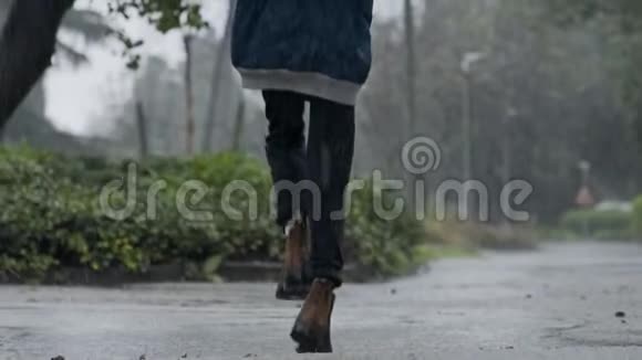 一个小男孩拿着雨伞在倾盆大雨中跳跃的缓慢动作视频的预览图