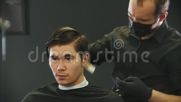 理发师在刷年轻人的客户湿头发在磁带镜子反射视频的预览图