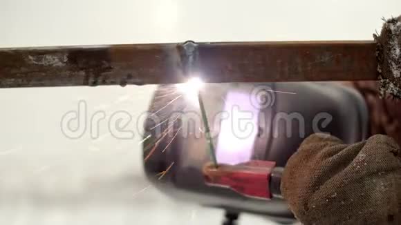 在金属上工作的焊条的特写一个戴防护面罩的人在焊接机上工作视频的预览图