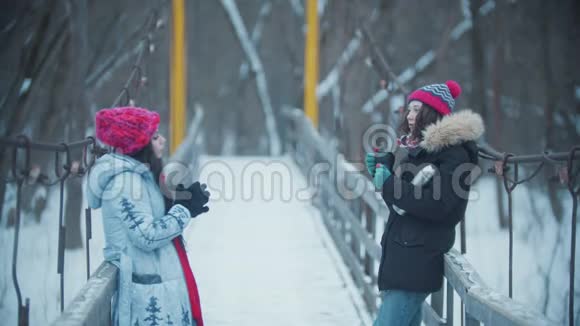 两个年轻的女人站在雪桥上聊天从热水瓶里喝热饮料视频的预览图
