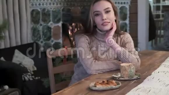 可爱的年轻亚洲美女坐在咖啡桌旁在壁炉边喝咖啡视频的预览图