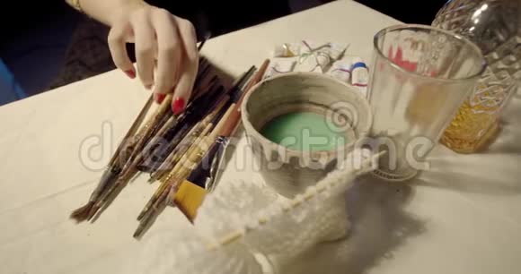 女人正在画画从桌子上拿出一把刷子上面有酒和一个玻璃杯视频的预览图