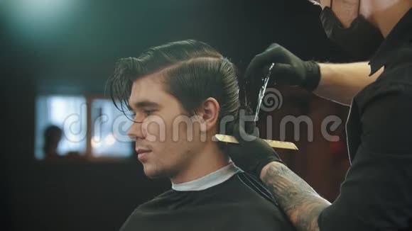 一个年轻男子在理发店理发时被纹身的理发师戴着手套视频的预览图